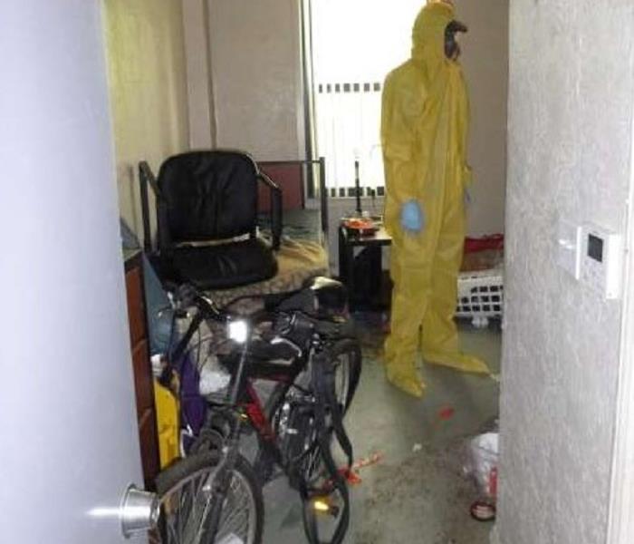 A man in bio-hazard attire standing in a home that needed cleaning