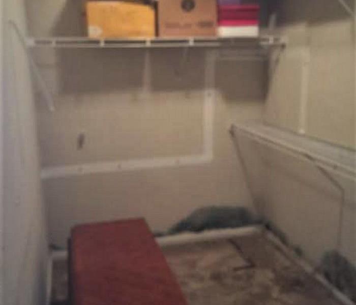 Master bedroom closet with contents and with mold on the walls and floors