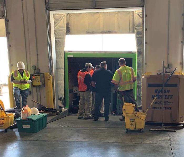 Staff together having a discussion in a building near a SERVPRO truck